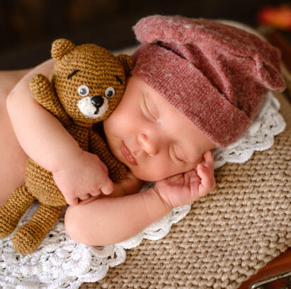baby sleeping well with teddy bear and beanie from coaching